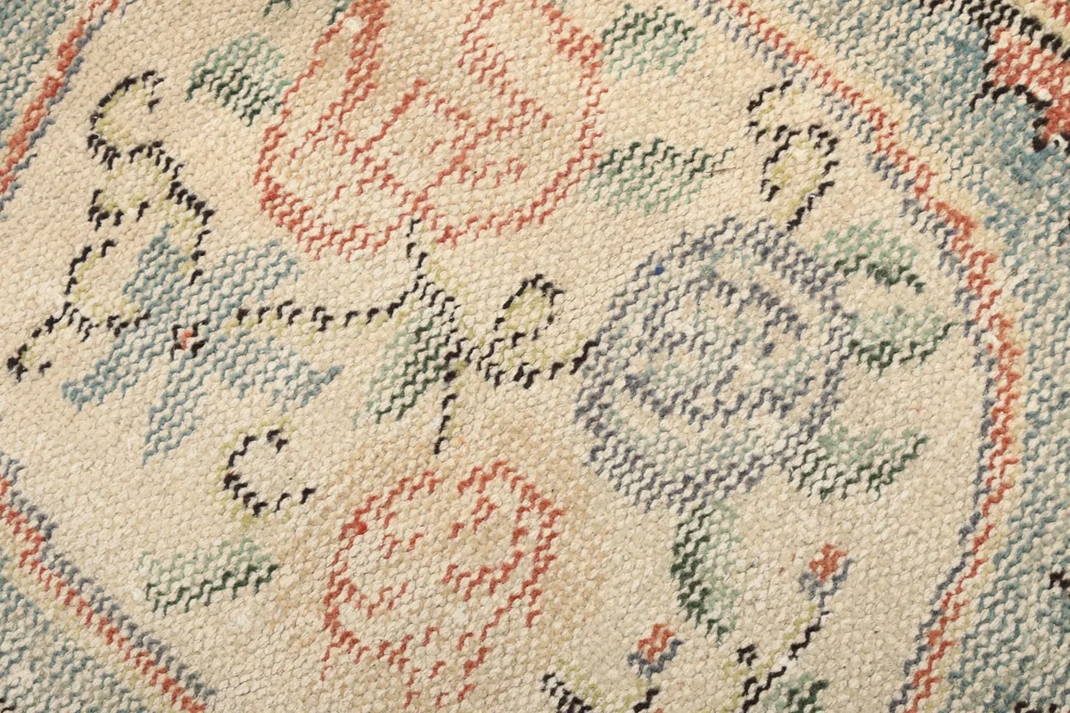 Close-up showing the low pile texture and hand-knotted details of the floral motif
