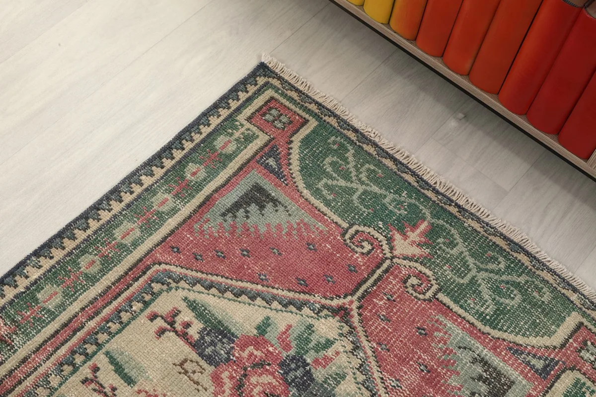 Detailed view of the green outer border and inner rose field at one corner of the rug.