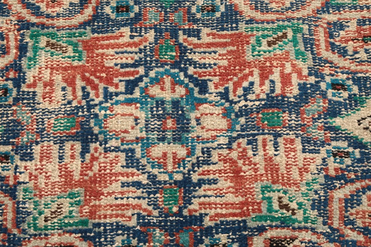 Texture and colors of the hand-knotted wool pile, showing vintage wear.