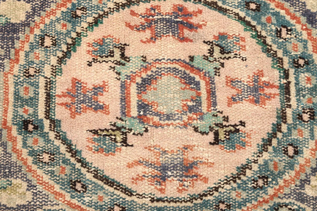 Intricate detail of the medallion's center with pink, blue, and rust threads