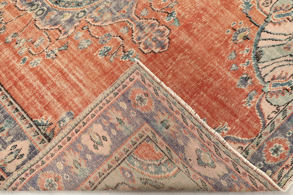 View of the rug's corner folded back, showing the back of the hand-knotted weave