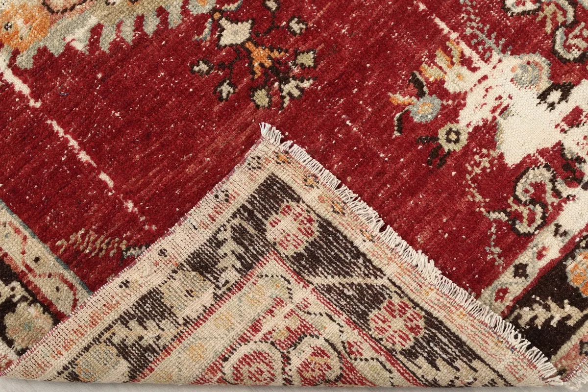 Corner of the rug folded back to show the hand-knotted cotton foundation and wool pile