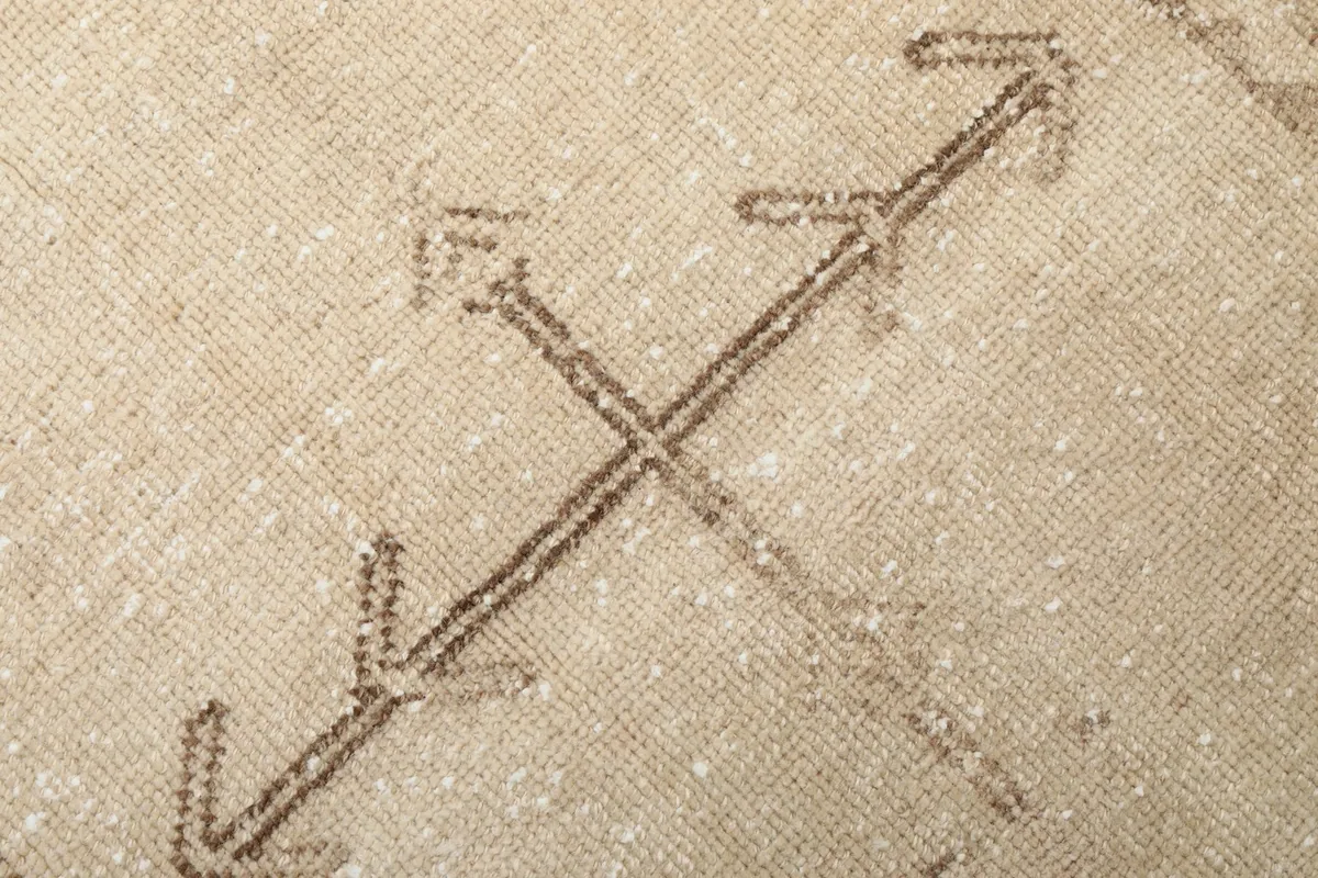 Extreme close-up of the brown geometric cross motif, showcasing the individual wool knots and distressed pile