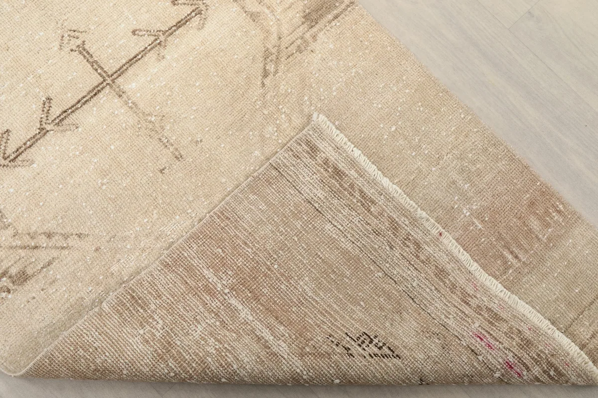 Corner of the rug folded back, revealing the cotton foundation and hand-knotted construction