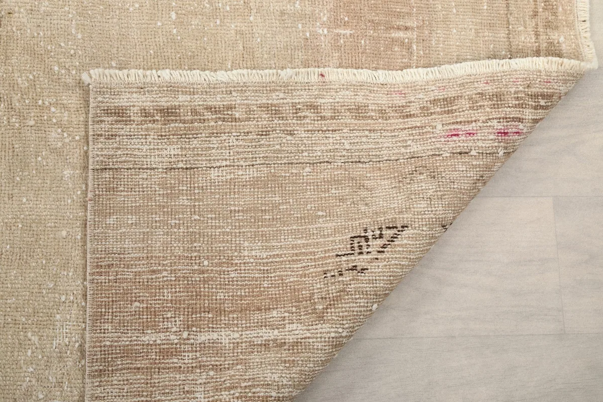 Detailed view of the rug's underside, showing the cotton foundation and professional cleaning marks