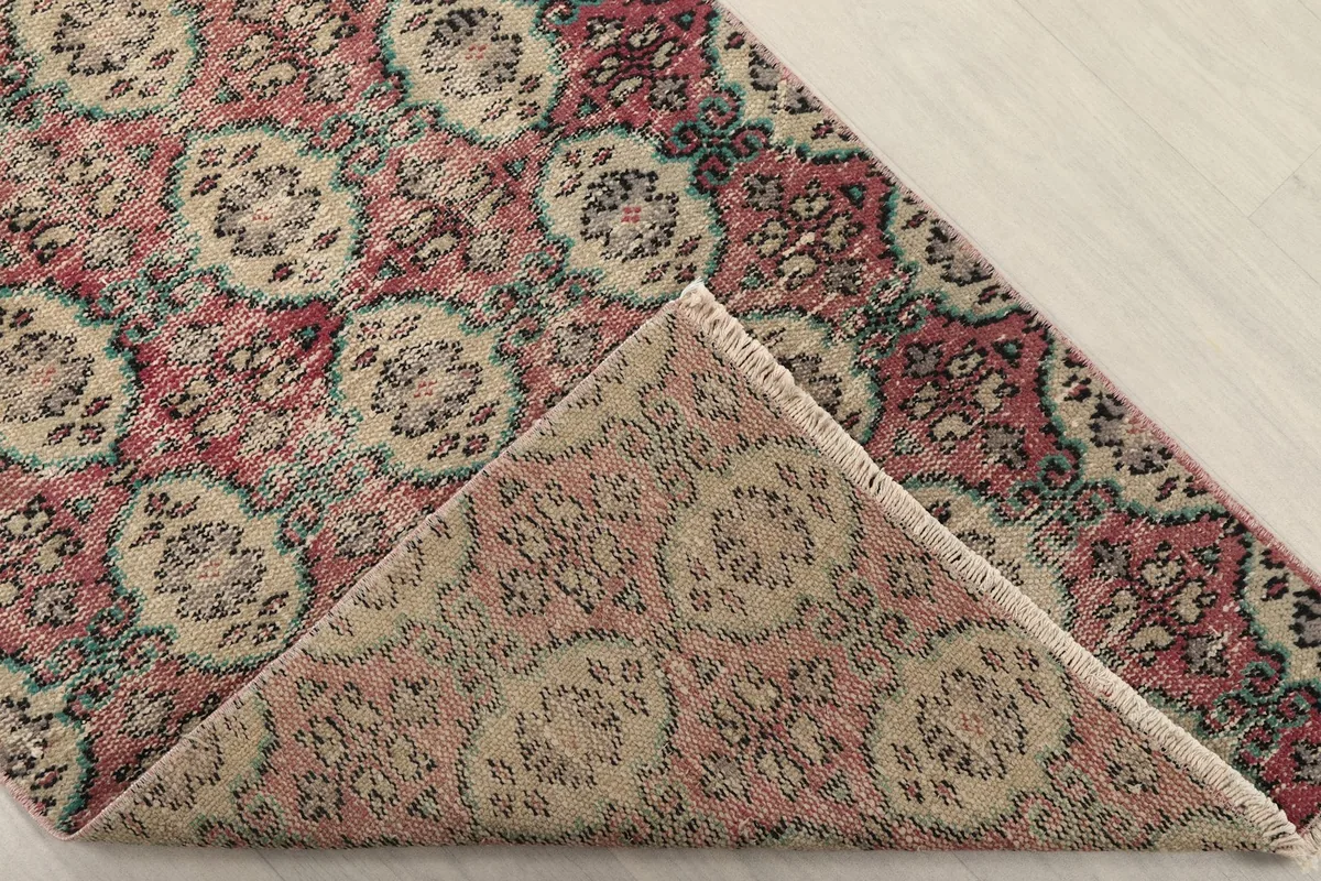Corner of the rug folded back to show the cotton foundation and the reverse side of the hand-knotted wool pile.