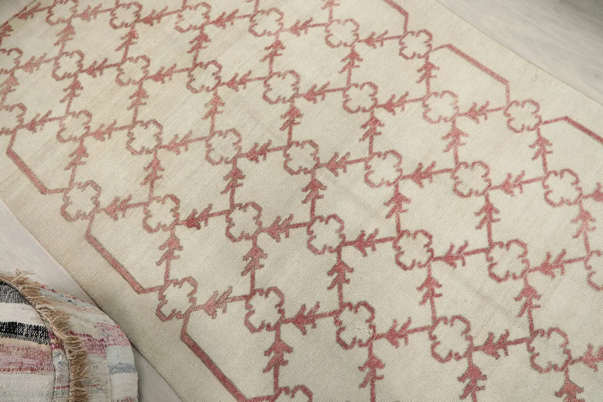 Angled view highlighting the overall rose geometric pattern on the ivory rug