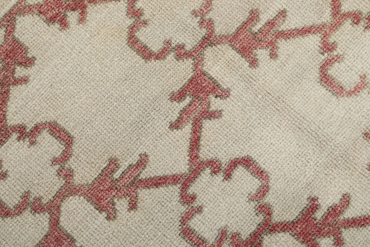 Close-up of the hand-knotted rose geometric pattern on the ivory wool pile