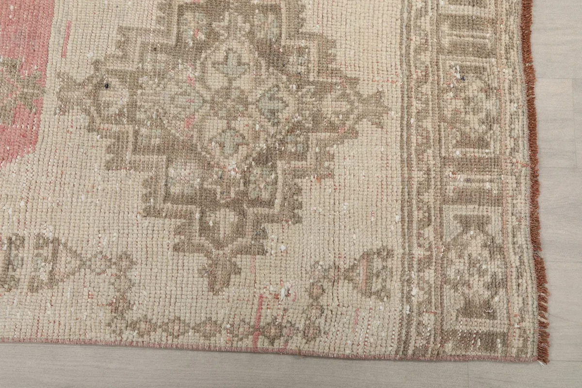 Detailed view of the beige section of the rug, showing geometric motifs and subtle wear