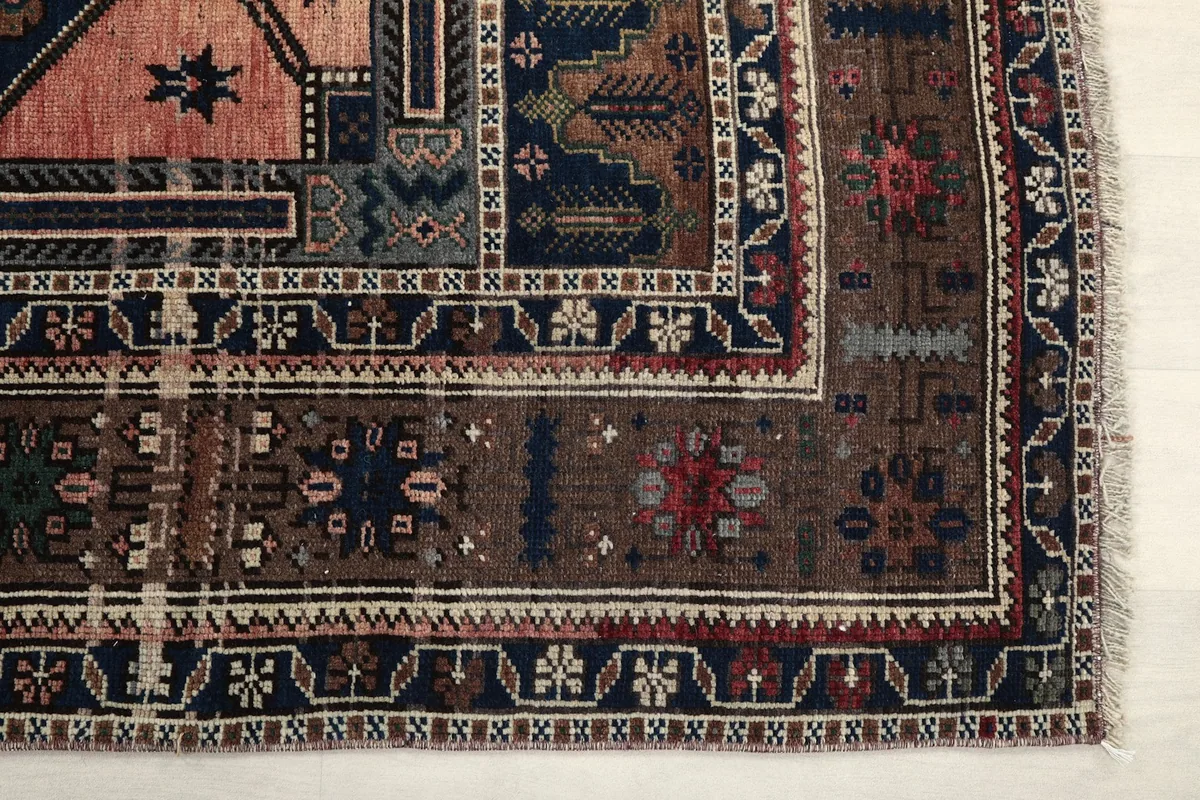 Detail of the intricate brown border and corner of the vintage rug, showing geometric patterns