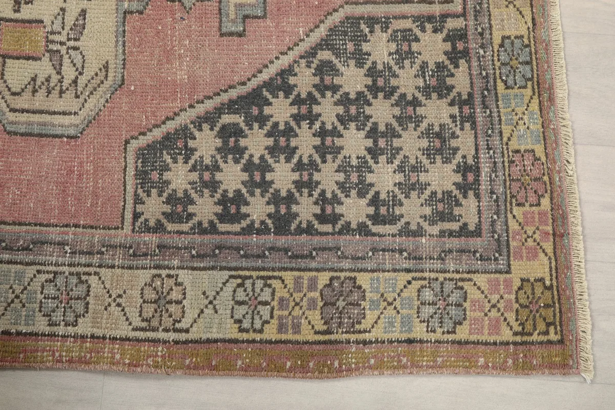 Detailed view of the rose rug's geometric patterns and floral border in cream and charcoal