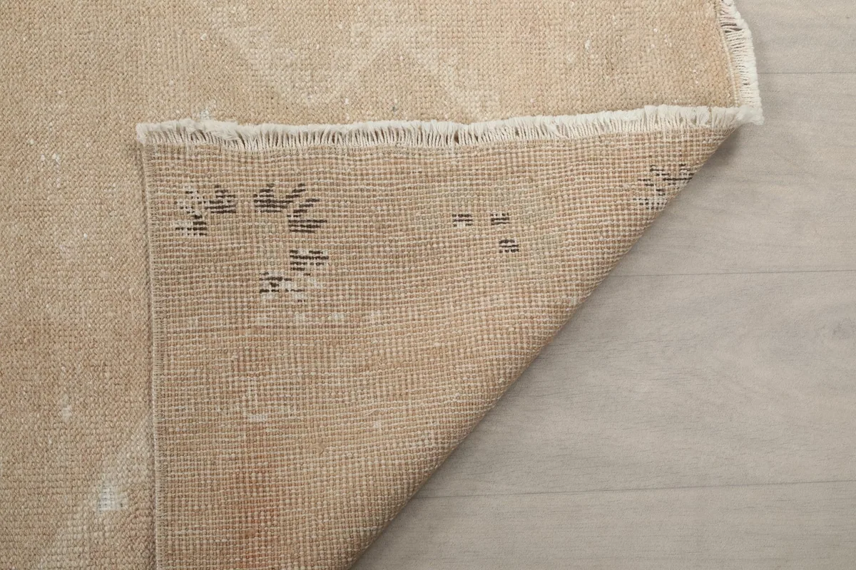 Underside of the runner rug, showing the cotton foundation and the knotting structure from the back