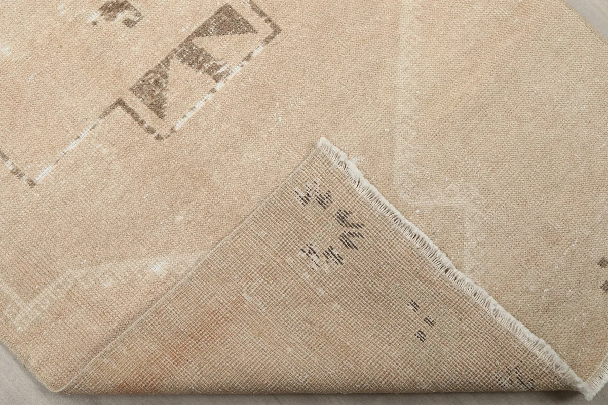 Corner of the rug folded back, revealing the hand-knotted cotton foundation and reverse side of the pile