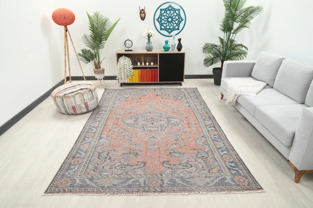 Vintage rust and blue Anatolian rug in a modern living room setting with a gray sofa.