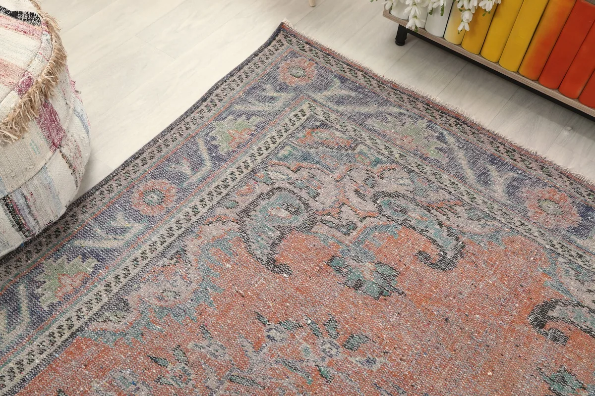 Corner detail of the rug, showing the blend of rust, blue, and gray tones.