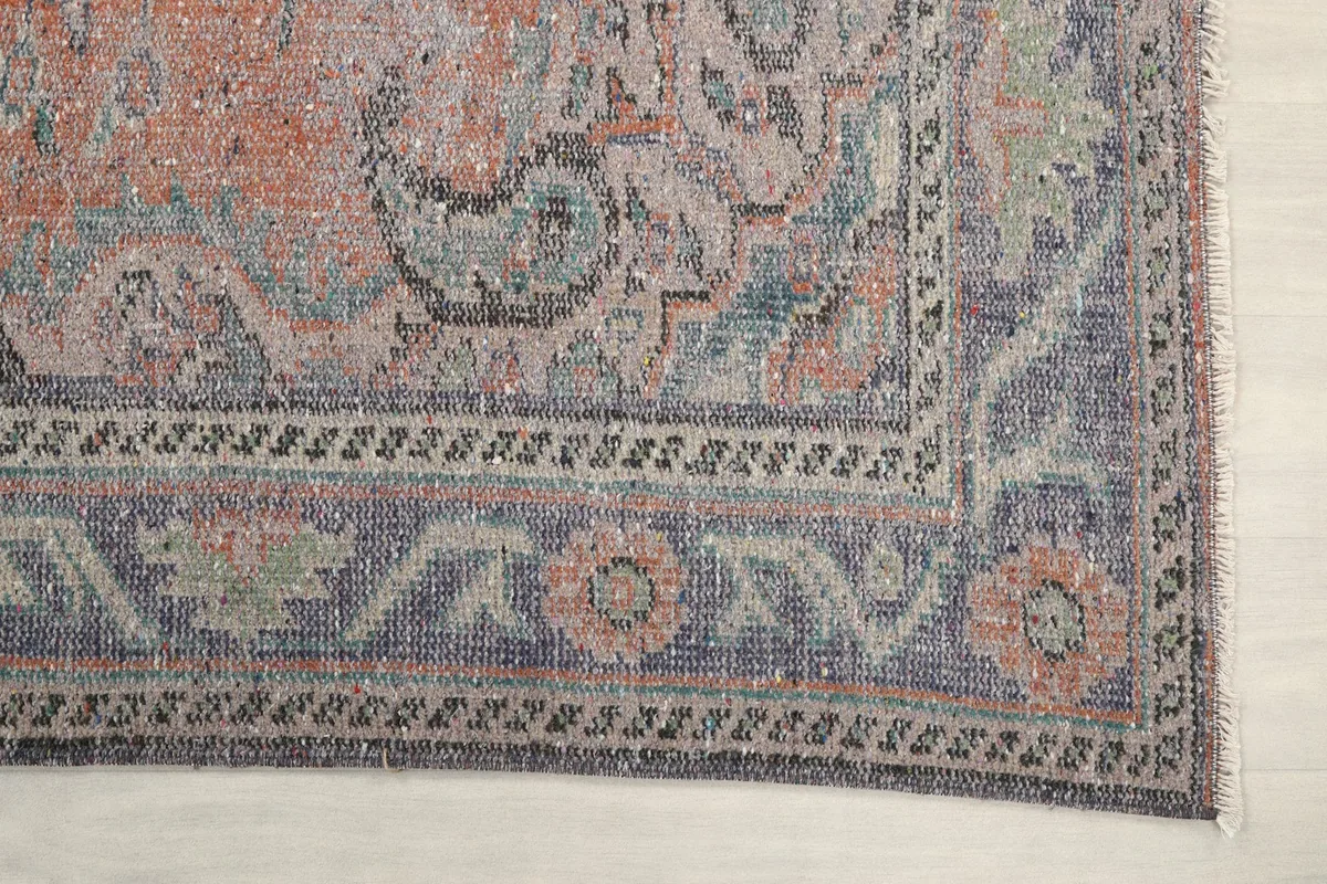 Detail of the rug's blue border with floral and geometric patterns in the corner.
