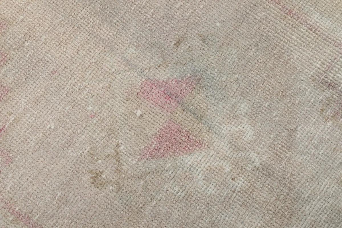 Extreme close-up of the low wool pile, revealing the hand-knotted texture and soft rose fibers