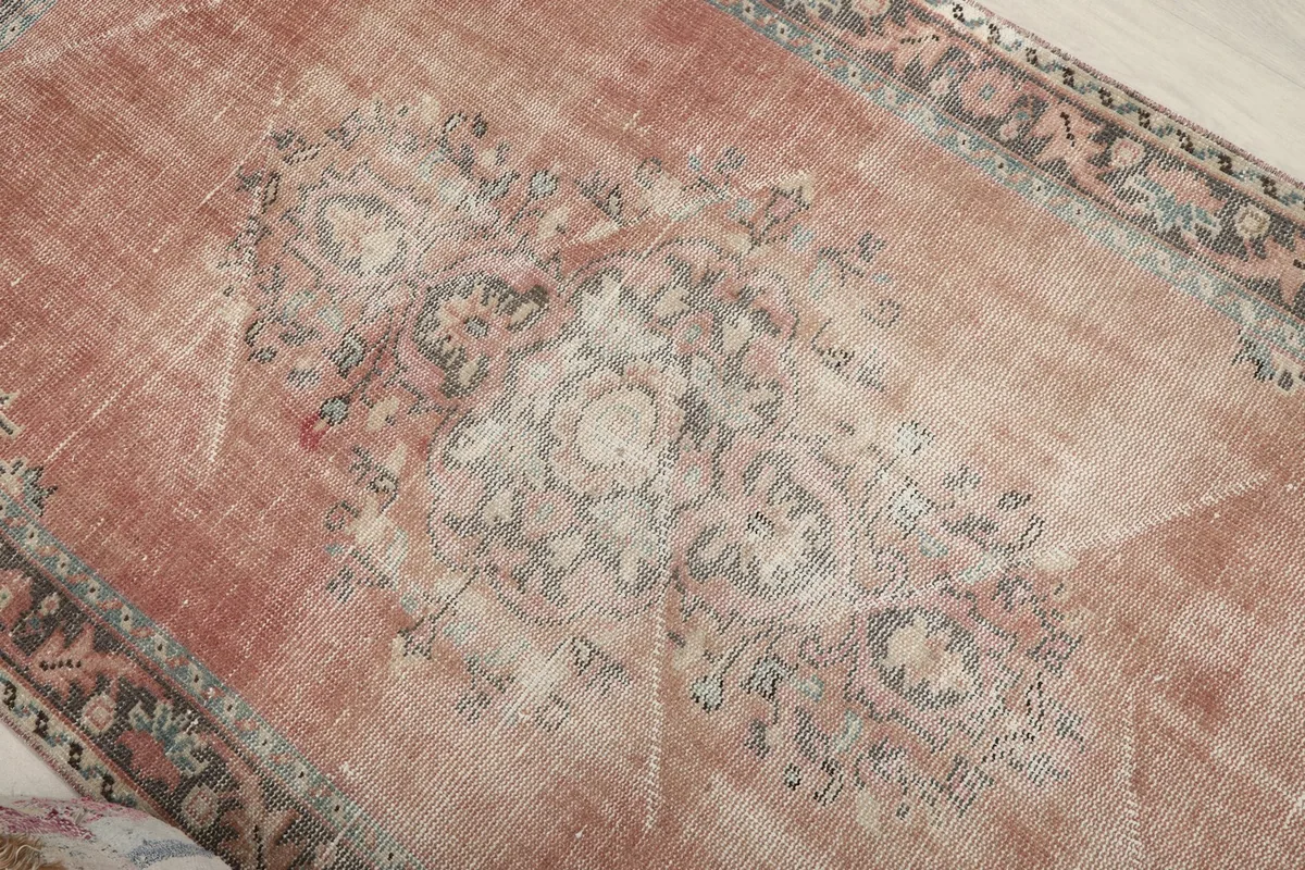 Close-up of the central medallion and field, highlighting the faded rose and cream tones.