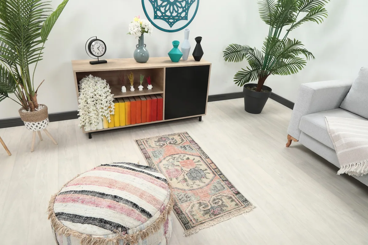 Overhead view of the vintage rug in a living space, showing its scale next to an ottoman and sofa.