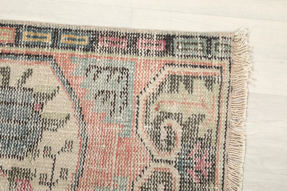 Close-up of the rug's top right corner, highlighting the border and faded colors.