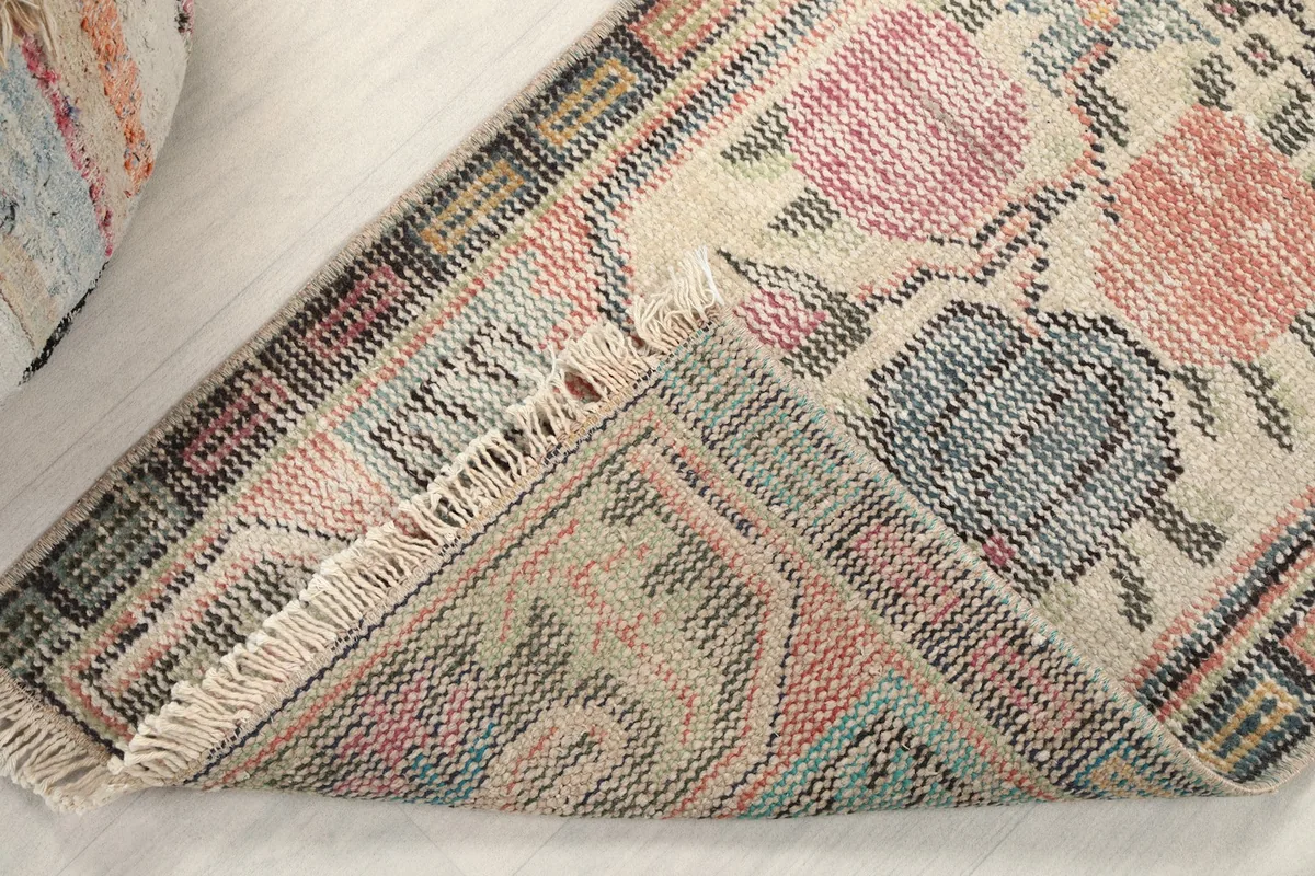 Corner view of the rug flipped to show the hand-knotted cotton foundation and back of the pile.