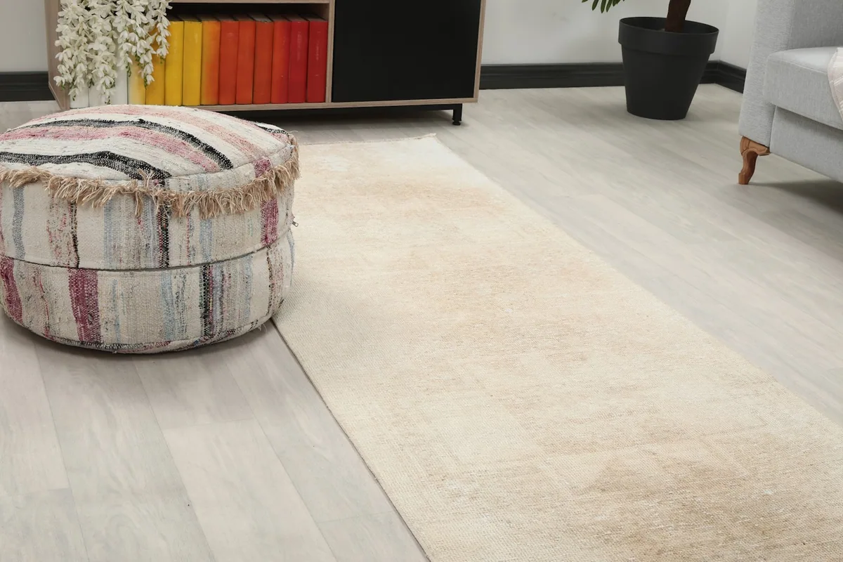 Close-up of the runner rug's texture and subtle geometric patterns next to a colorful ottoman.