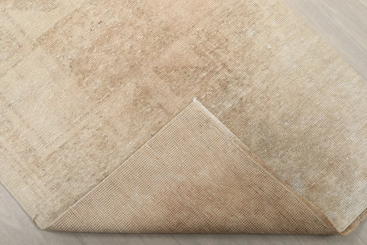 Corner of the rug folded back to reveal the cotton foundation and hand-knotted construction.