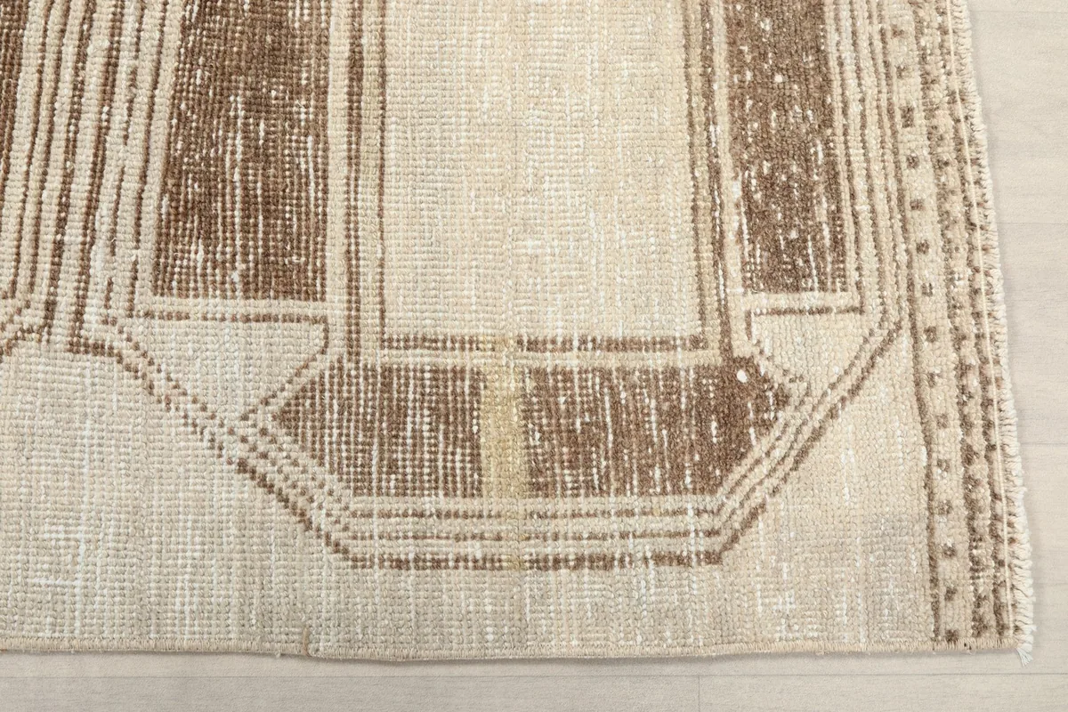 Detailed view of the brown geometric motif on the ivory field of the rug