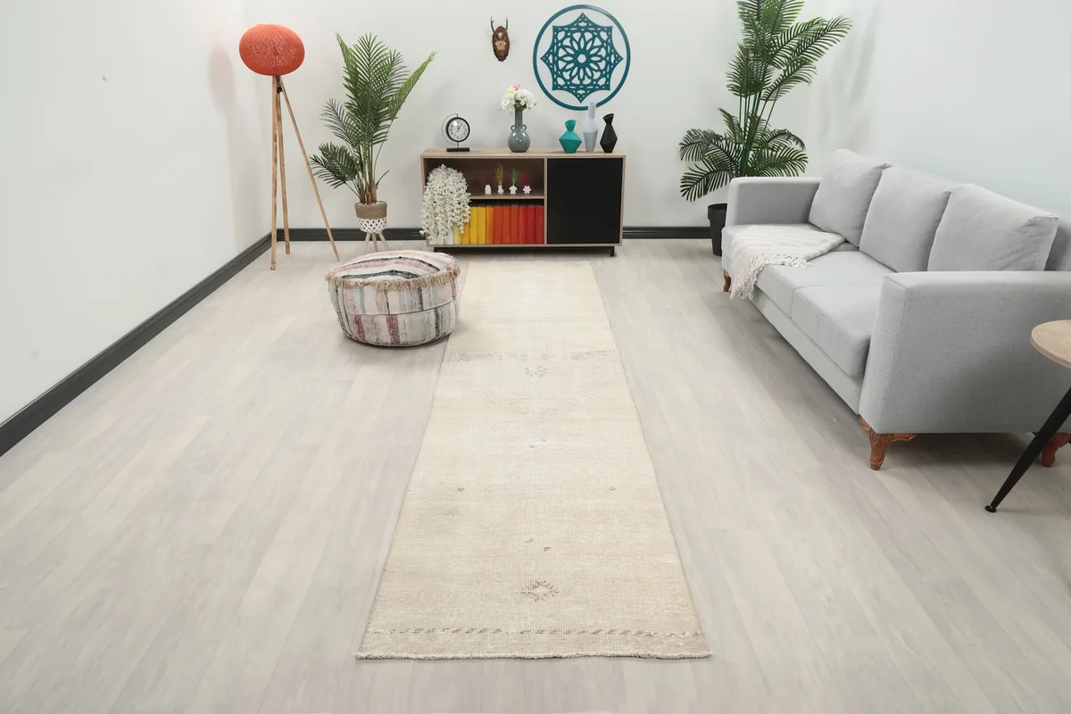 Beige vintage runner rug in a living room setting, showing its long dimension next to a sofa.