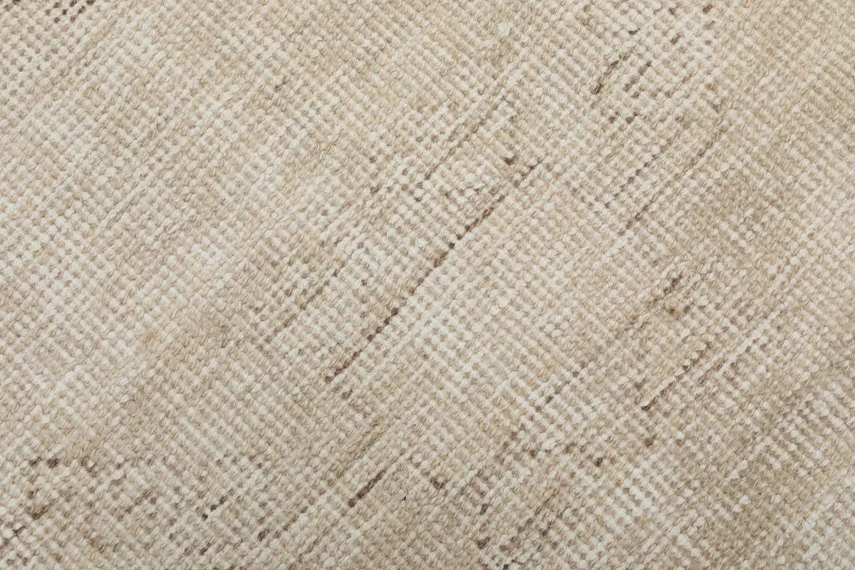 Texture shot of the rug's low wool pile, revealing the hand-knotted construction and natural fiber variations.
