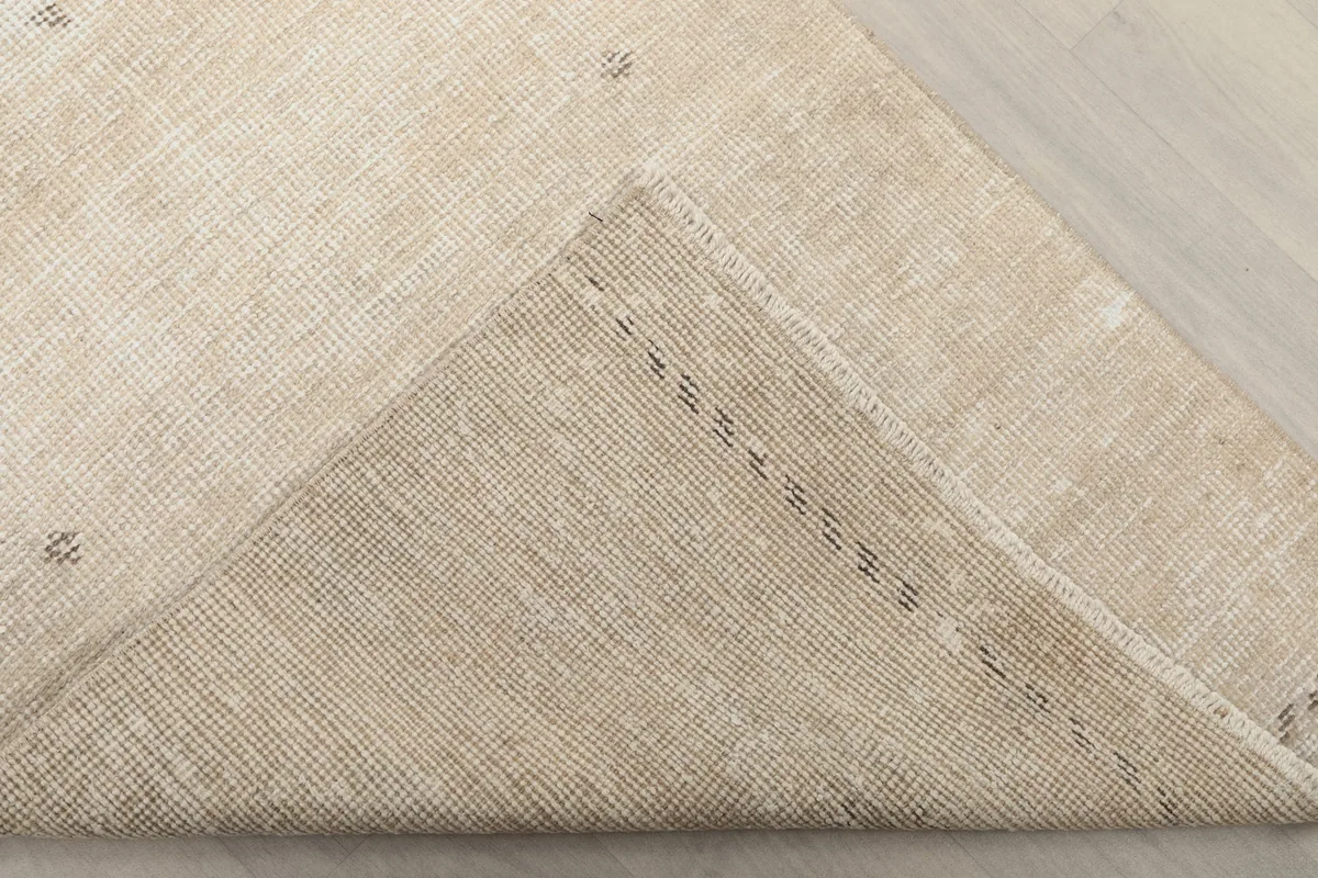 Underside view of a folded corner of the rug, showing the cotton foundation and hand-knotted construction.