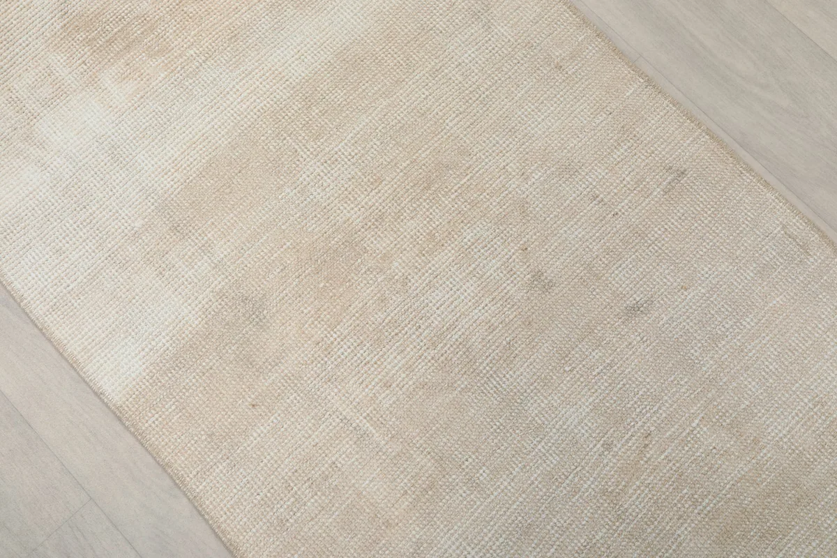 Angled close-up of the beige runner rug's texture and natural variations in color
