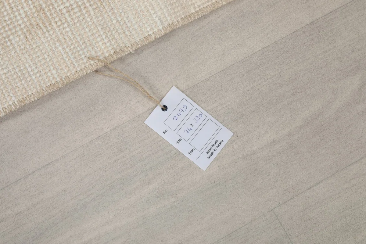 Product tag displaying the rug's dimensions and origin, resting on the floor