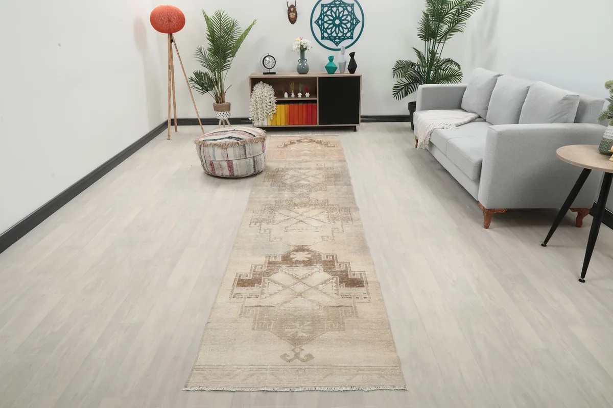 Long ivory and brown runner rug laid out in a living room with a gray sofa and light wood floor