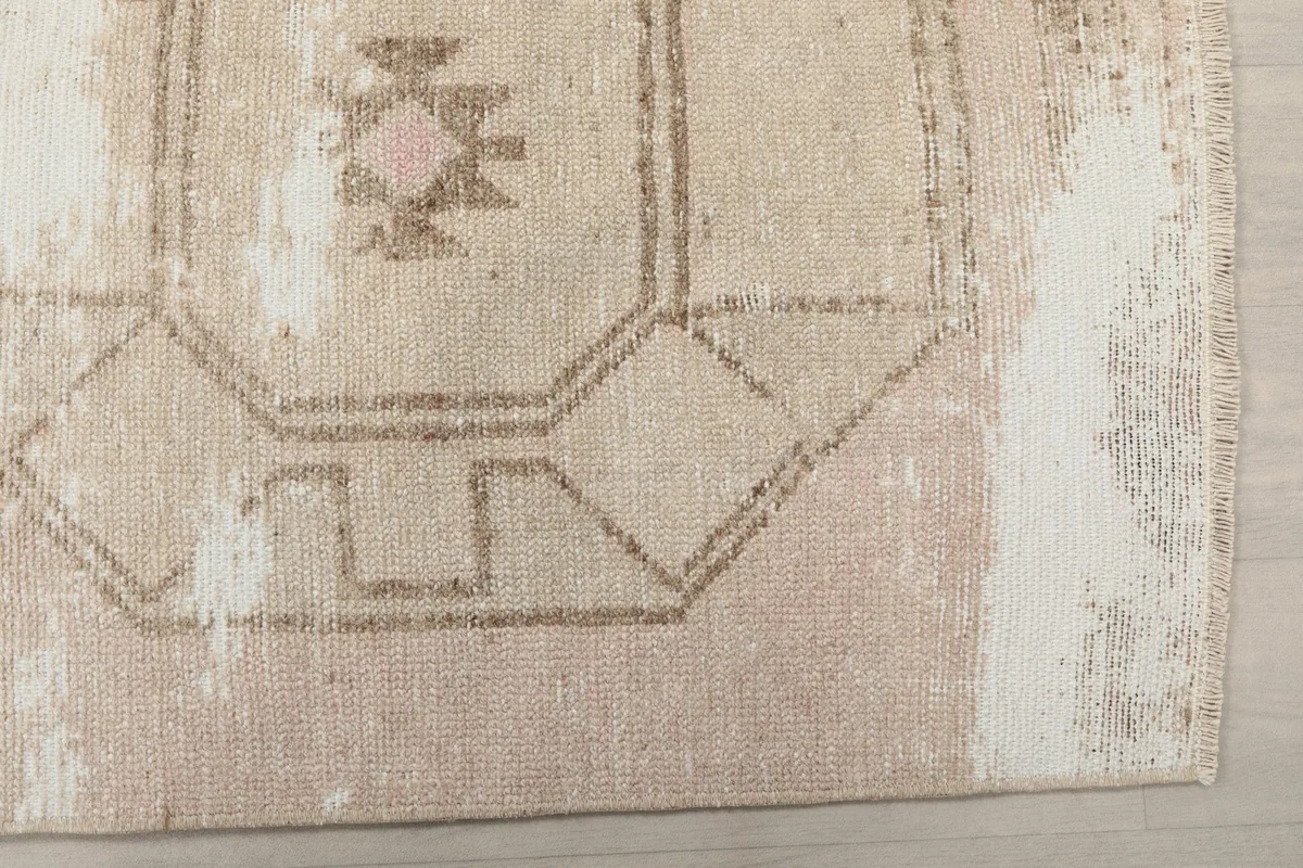 Detailed view of the rug's geometric pattern and distressed texture with ivory highlights