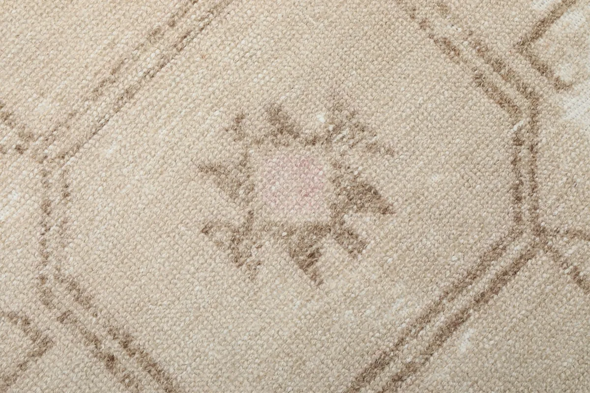 Close-up on a geometric motif with rose and brown accents, highlighting the knotting