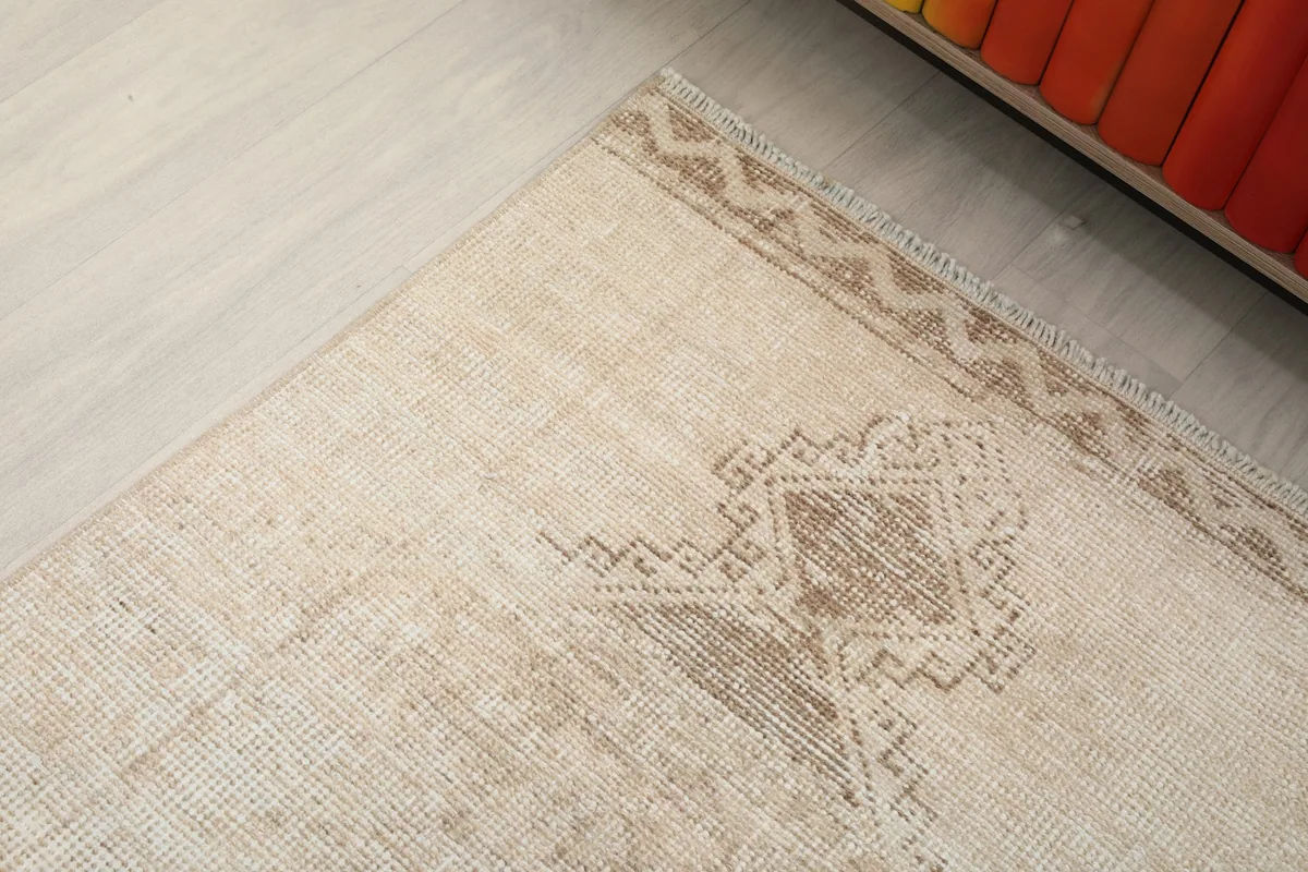 Close-up of the rug's end, revealing a faded tan geometric border and central motif