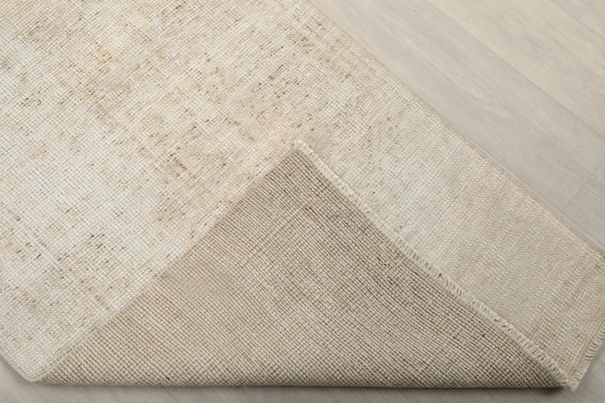 Corner of the rug folded over to display the hand-knotted cotton foundation from the back