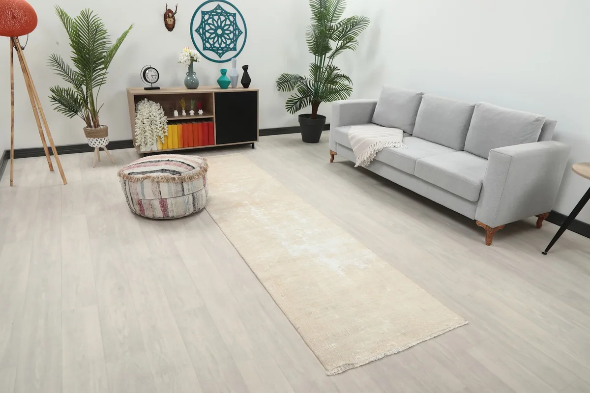 Side angle view of the beige Anatolian runner rug in a room with a sofa and decorative elements.