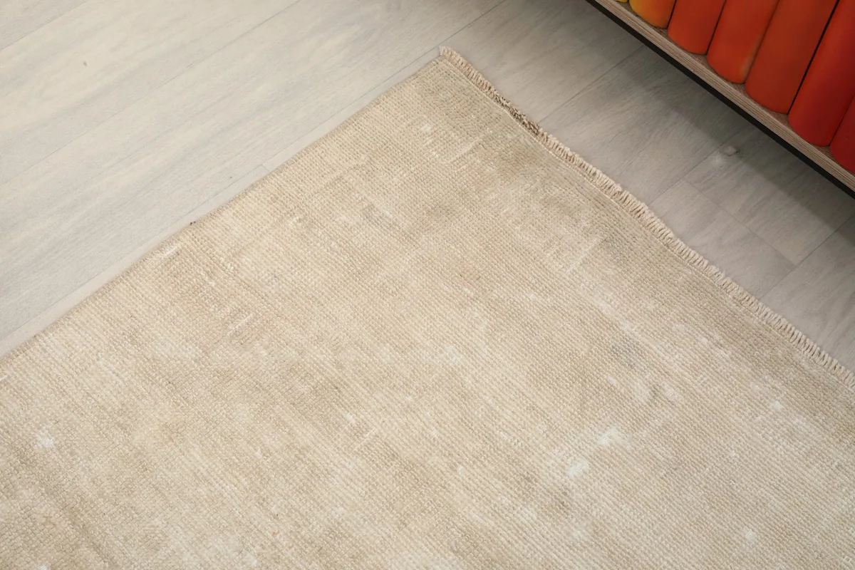Close-up of a corner of the beige runner, revealing the natural wear and original edge finishing.