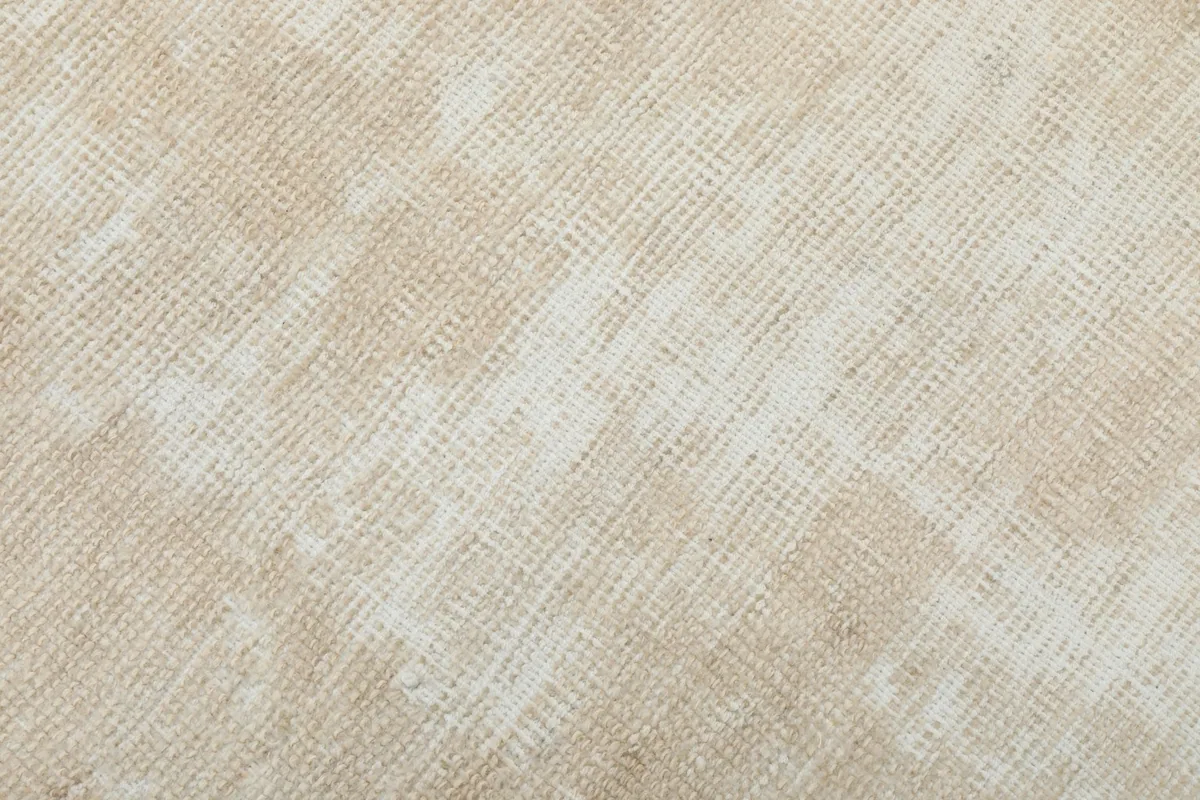 Close-up of the low wool pile, showing the hand-knotted texture and natural variations in the beige color.