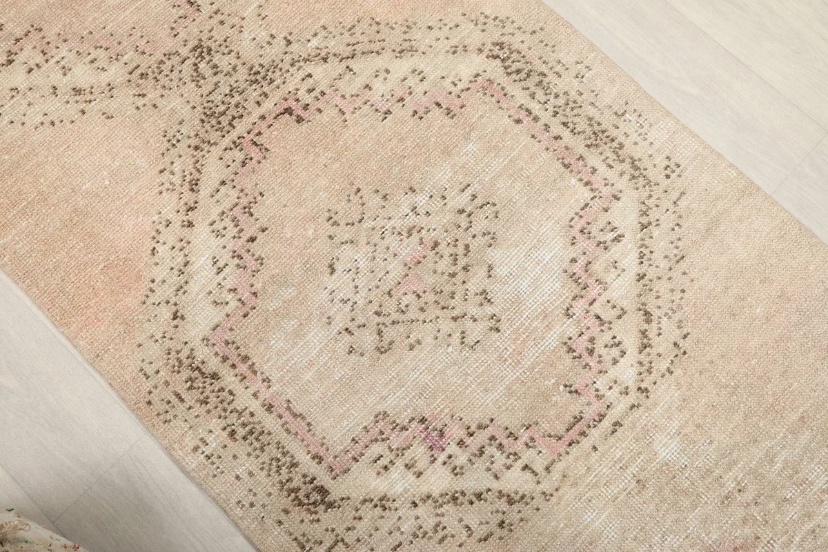 Close-up of the rug's central medallion with faded rose and brown geometric patterns.