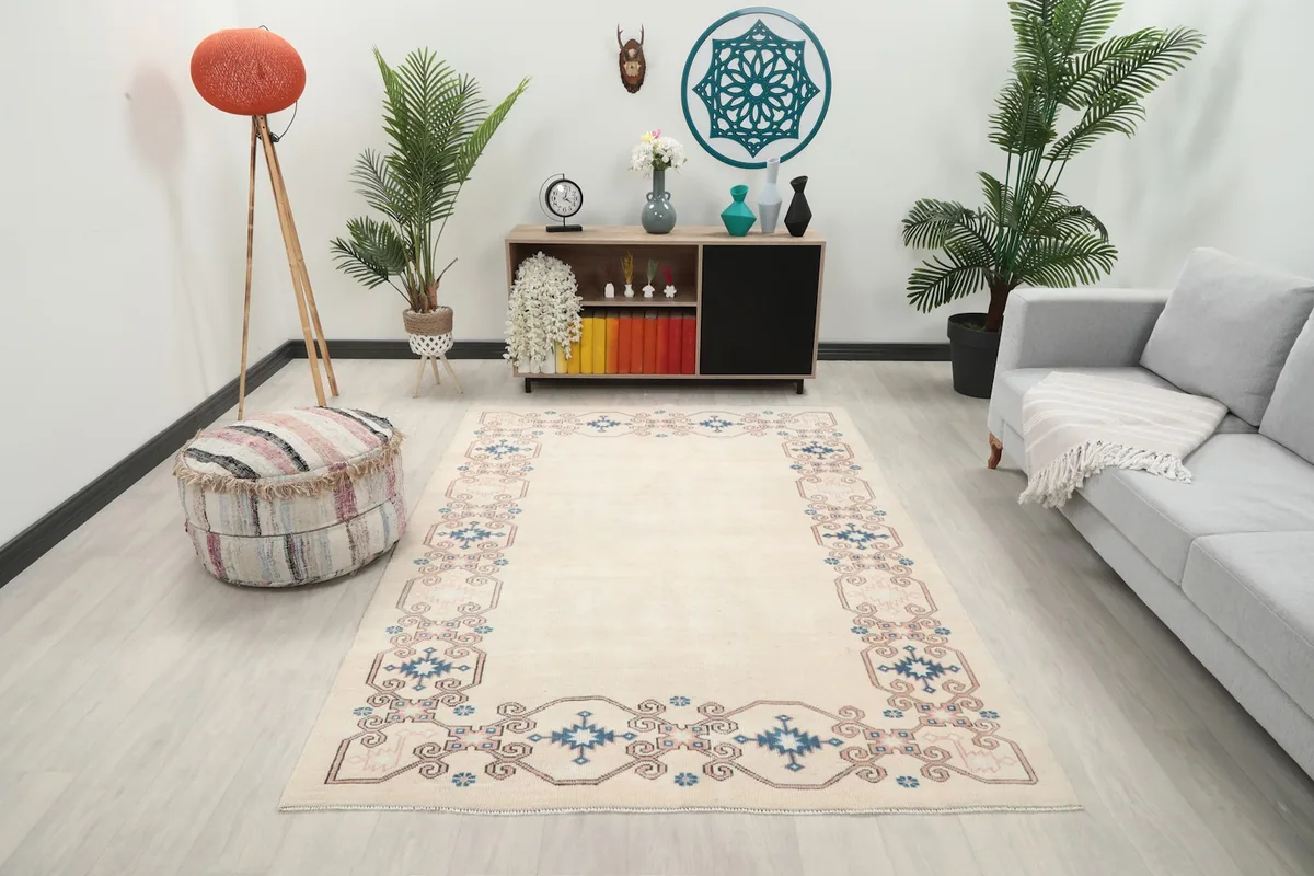 Vintage ivory rug displayed in a living room setting with a gray couch and wooden furniture