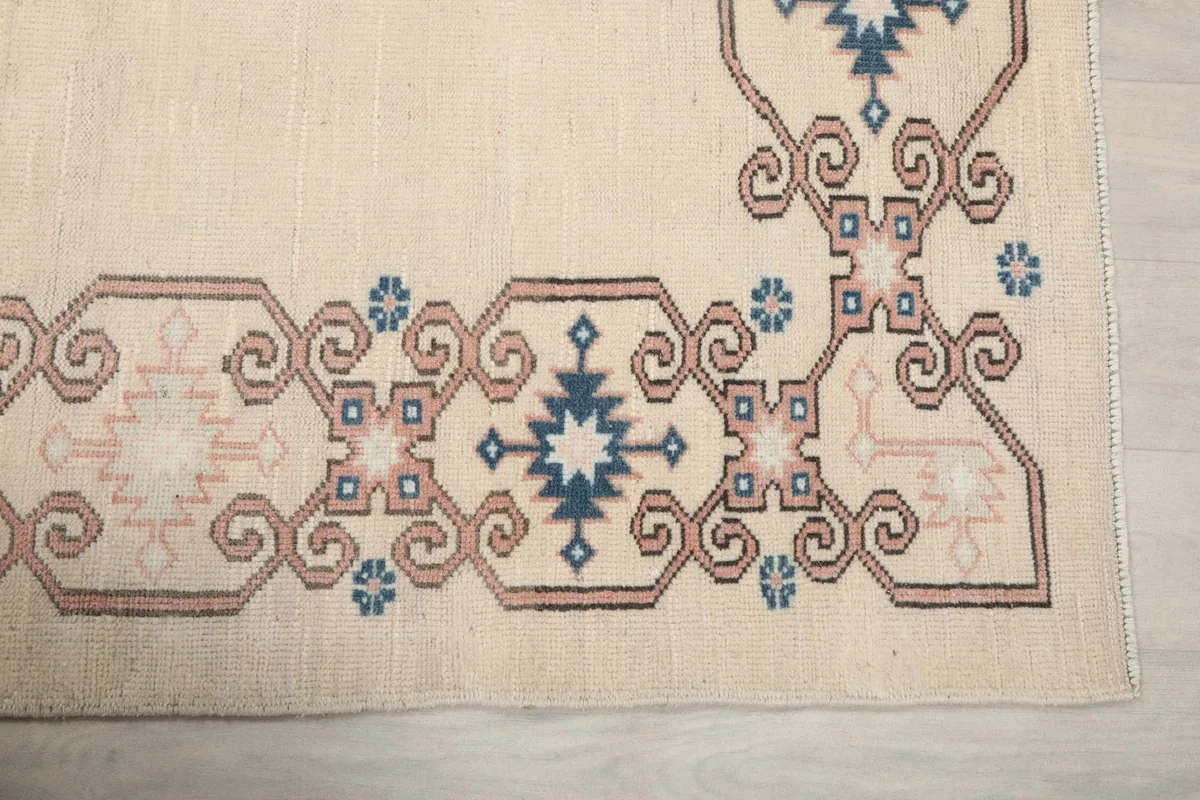 Detailed view of the corner of the rug, highlighting the blue and pink tribal motifs