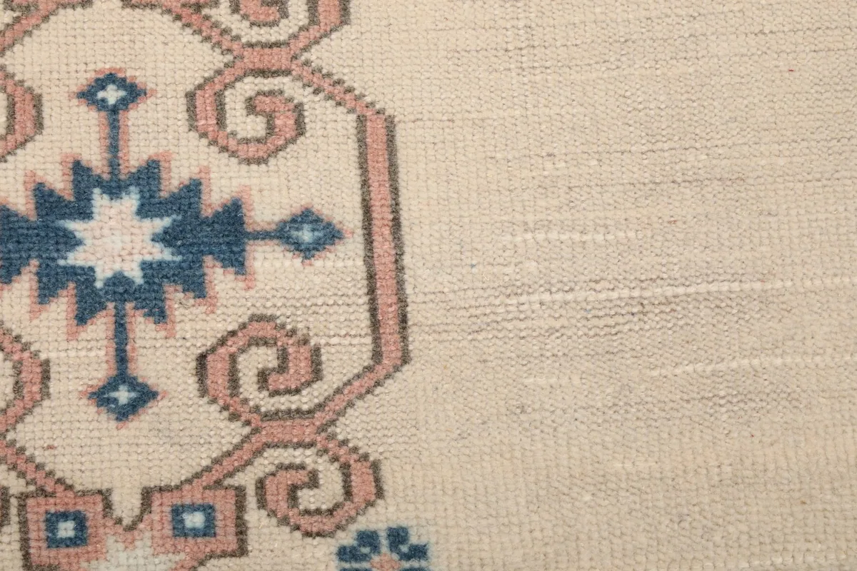 Close-up of the wool pile texture and the hand-knotted construction of the ivory rug