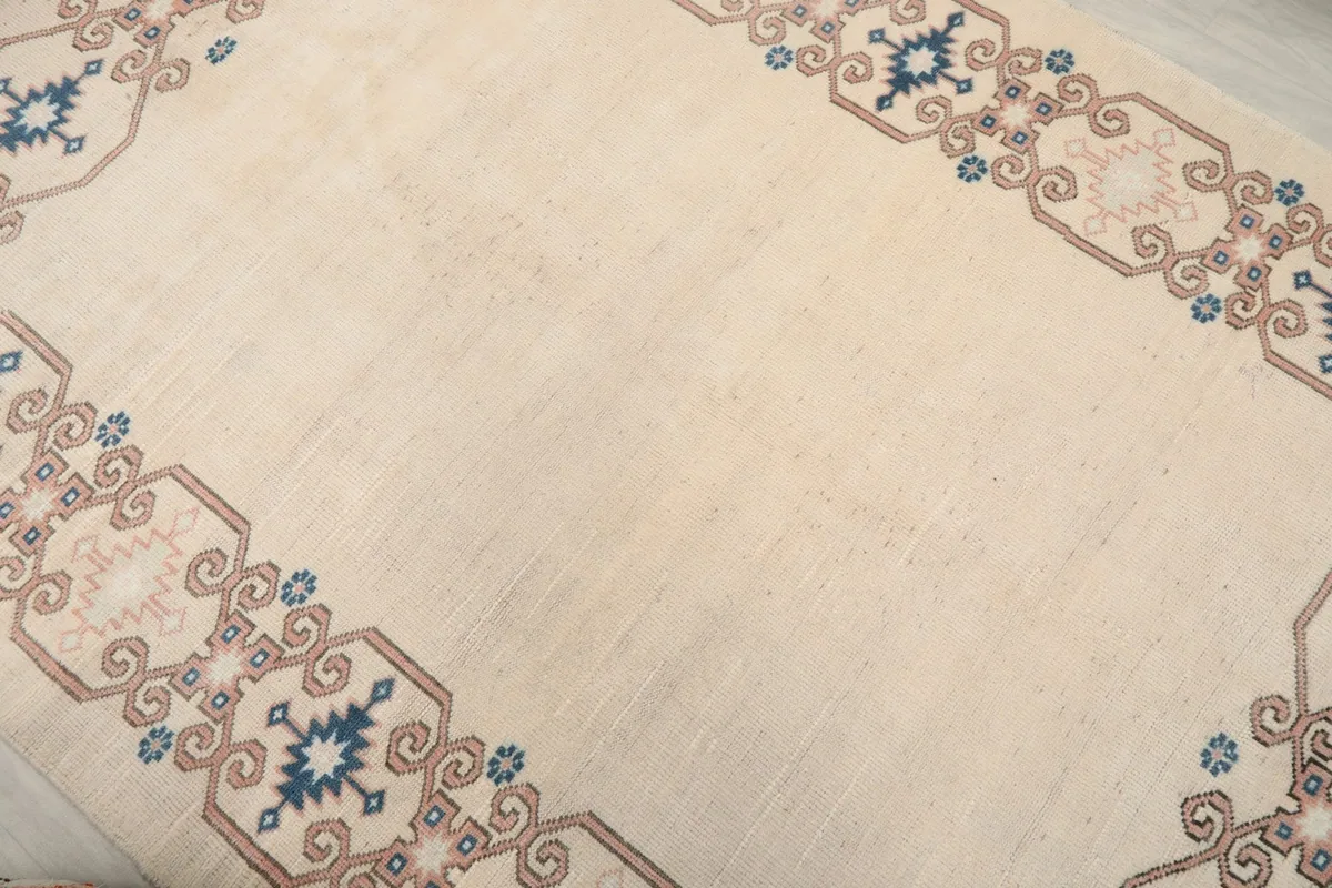 Overhead shot of the ivory rug, focusing on the subtle patina and the border design