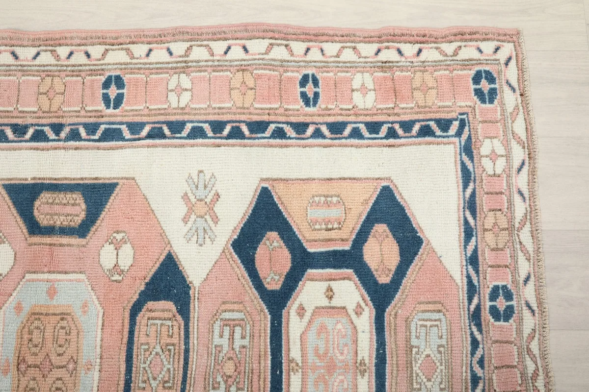 Detailed view of the rug's top right corner, showcasing the rose border and navy geometric motifs