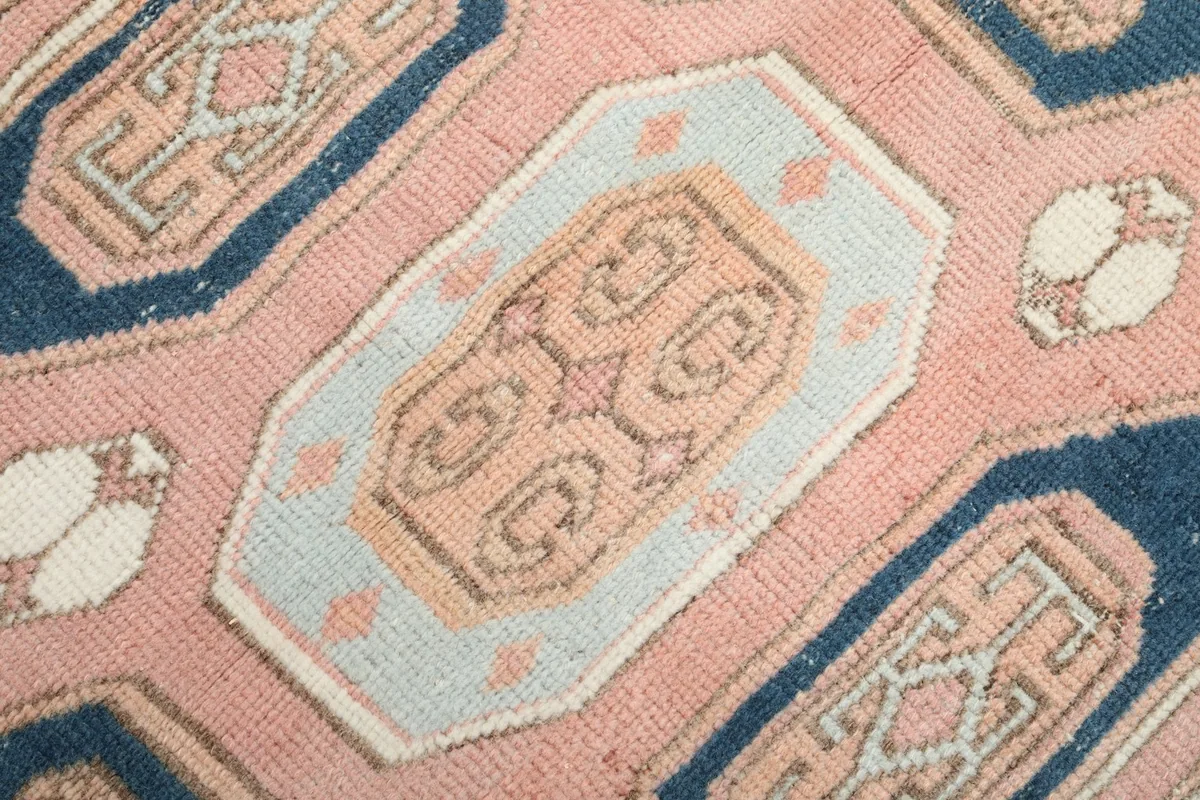 Close-up detail of a central geometric medallion, showing the subtle rose, gold, and light blue tones