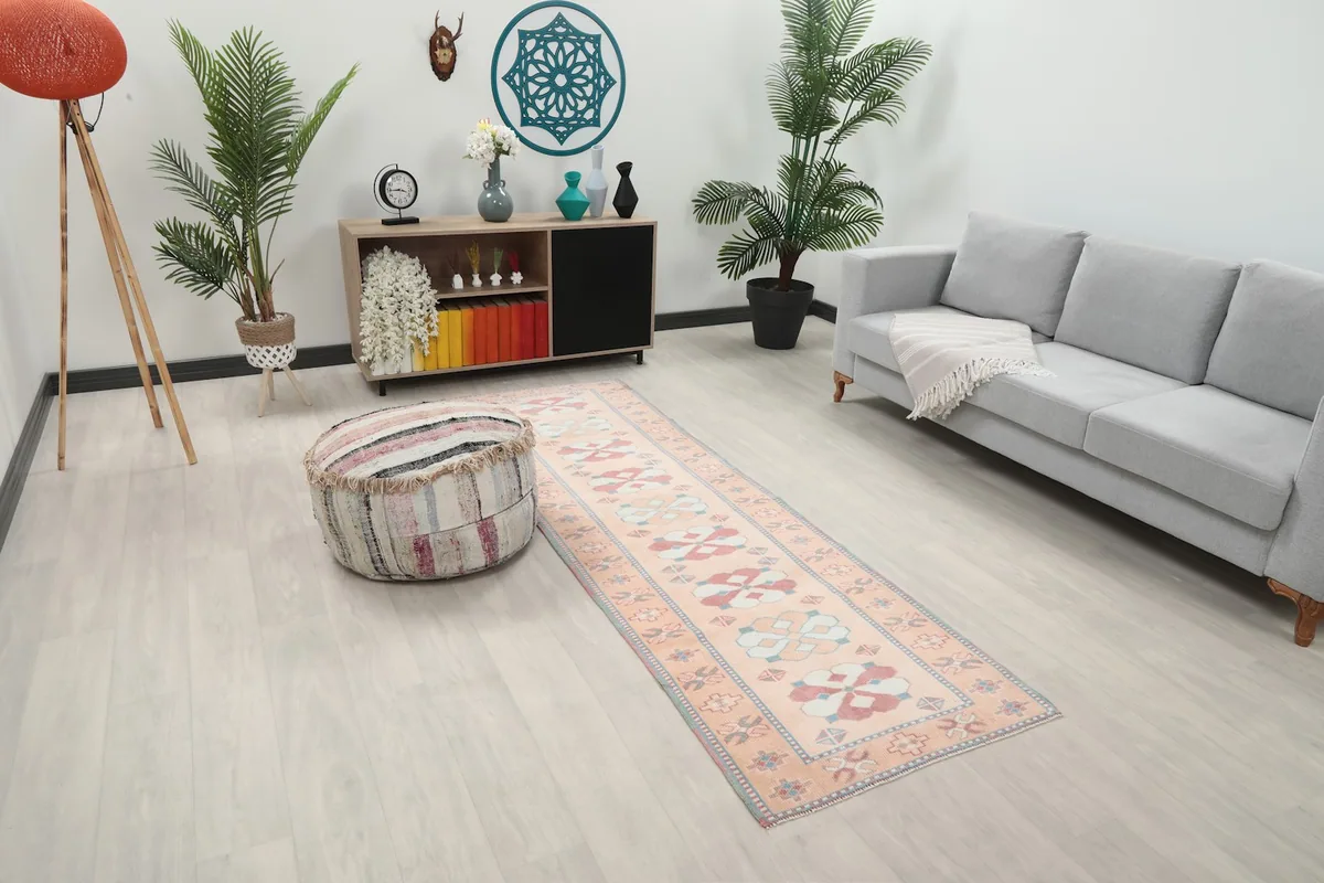 Runner rug shown in a room with a light-colored sofa and a striped ottoman