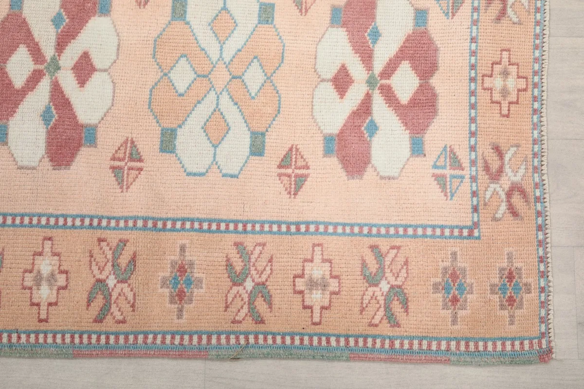Detailed view of the rose, cream, and blue geometric motifs and border design